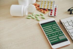 Smartphone and pills scattered on table