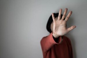 A woman covers her face with her hands.