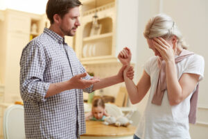 Angry man holding his worried wife arm during quarrel at home